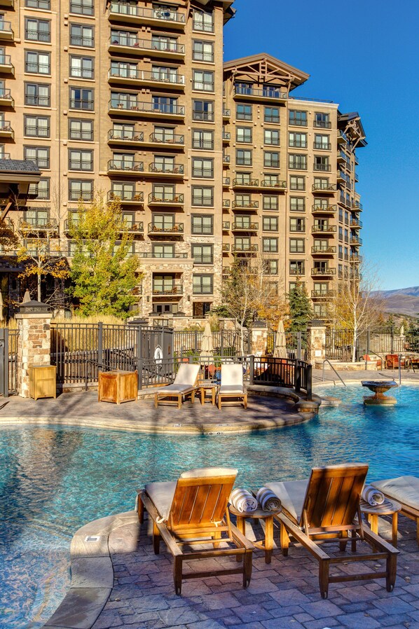 A hotel with a pool area featuring lounge chairs and a stone pathway.