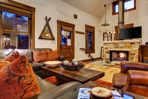 A cozy living room with a stone fireplace, leather sofas, and a large flat-screen TV. - Abode at Town Lift (Park City)