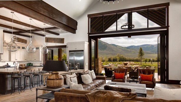 A spacious living area with a large sofa, a coffee table, and a view of a mountainous landscape through a large window. - Abode at Twilight Ranch (Oakley)