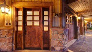 Puerta de madera con base de piedra, una placa con un número y un porche con techo de madera.