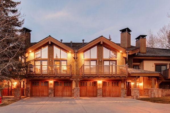 A large, multi-story house with a prominent balcony, large windows, and a stone facade.