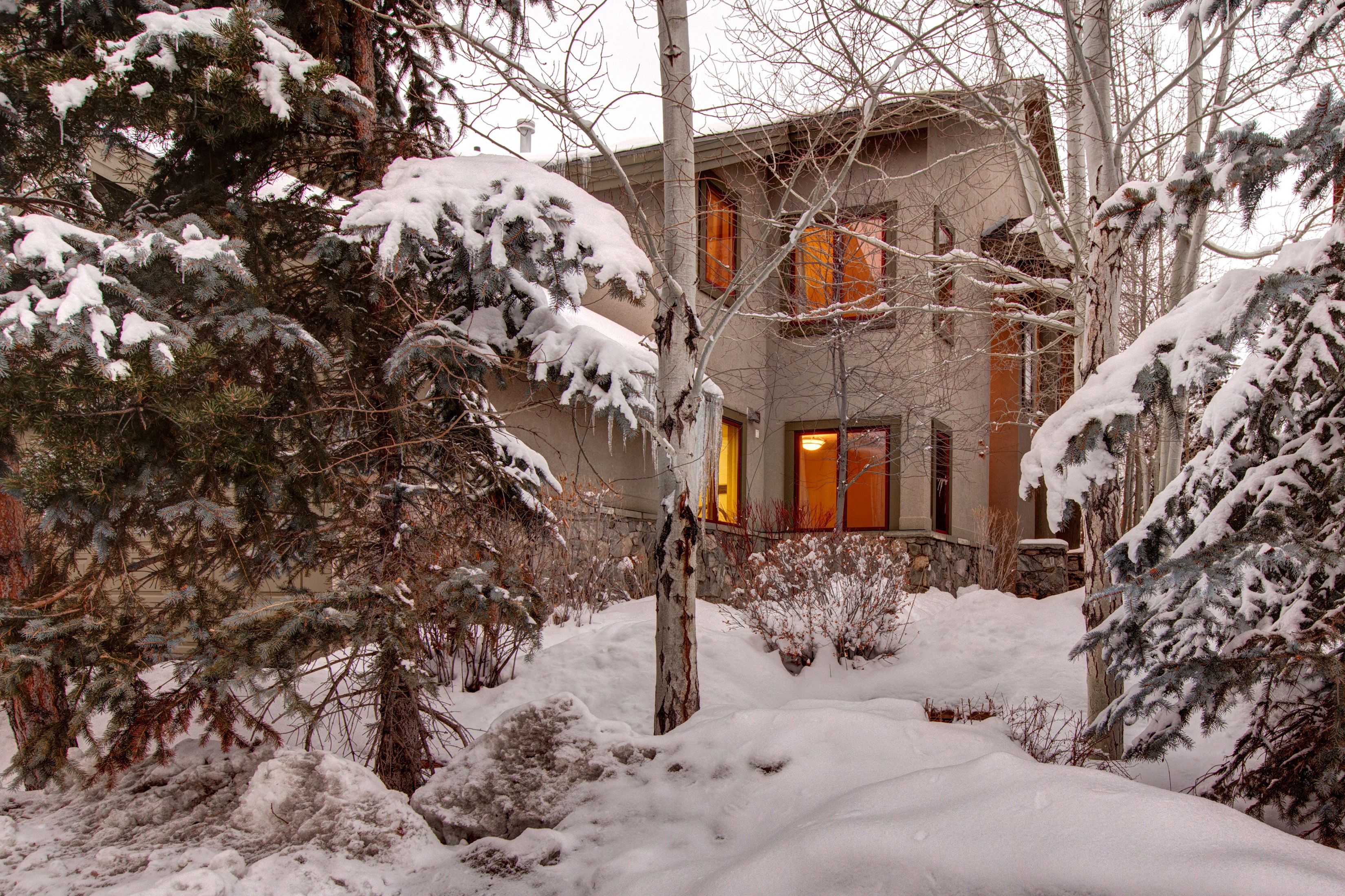 A snow-covered landscape with a building featuring a stone facade and a warm-lit entrance.