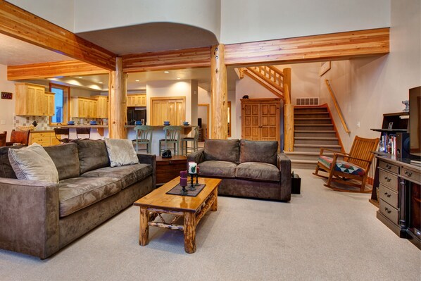 A spacious living room with a large wooden coffee table, two sofas, and a staircase leading to an upper level.