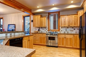 A kitchen with wooden cabinets, a stainless steel oven, and granite countertops. - Abode on Nakoma (Park City)