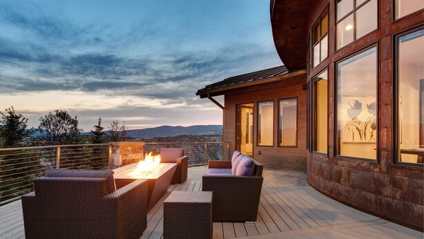 Eine Terrasse mit Korbmöbeln und einem Feuerbereich, mit Blick auf eine gebirgige Landschaft.