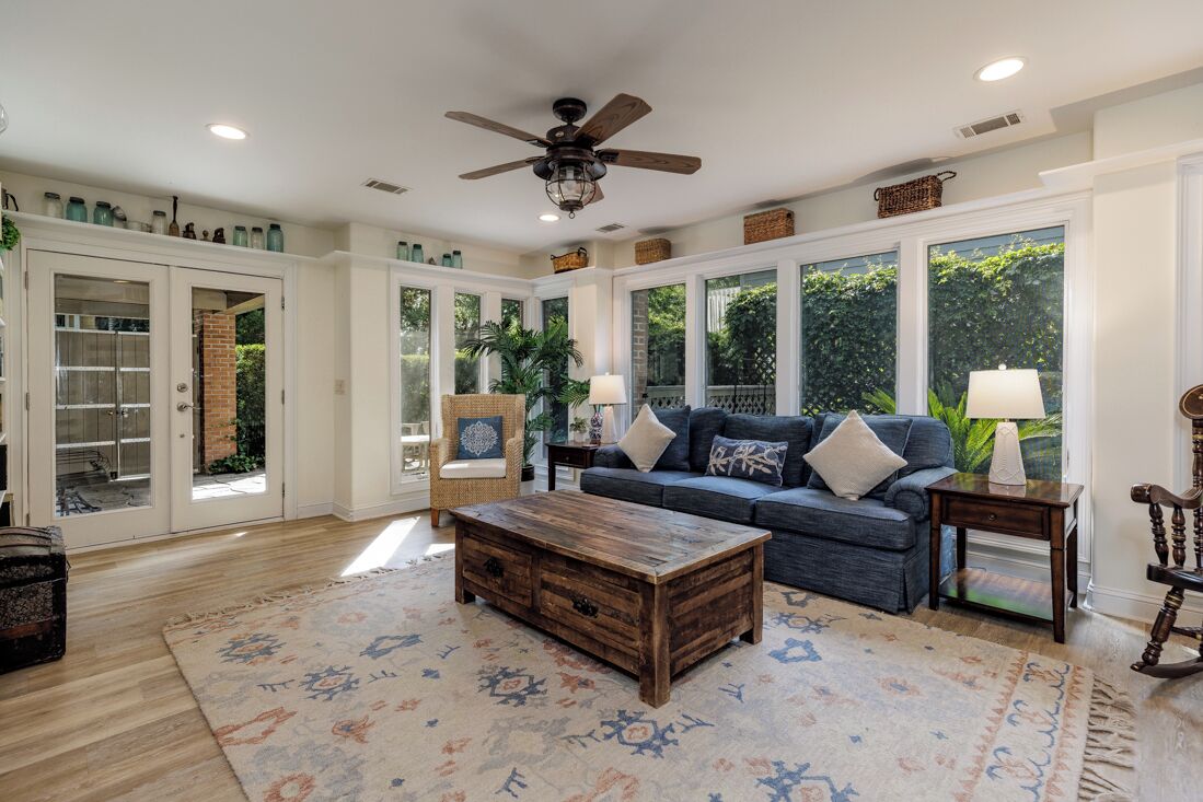 A spacious living room with a large window, a ceiling fan, and a wooden coffee table.