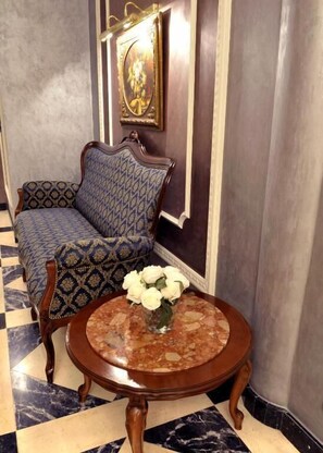 A room with a patterned sofa, a round table with a vase of white flowers, and a framed picture on the wall. - Willa Alexander Resort & SPA (Mielno)
