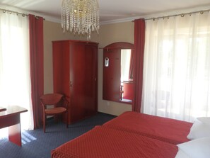 A hotel room with a bed, a desk, a chair, a wardrobe, and a chandelier. - Willa Alexander Resort & SPA (Mielno)