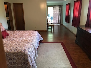 A bedroom with a bed, a dresser, a chair, and a view of the outside through a window. - Tanglewood Lodge (Rogers)