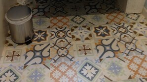 A bathroom with a white sink, two drawers, and a trash bin. The floor has patterned tiles.