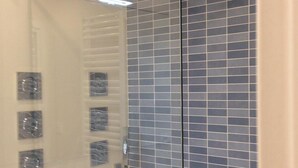 A glass-enclosed shower with a tiled wall.