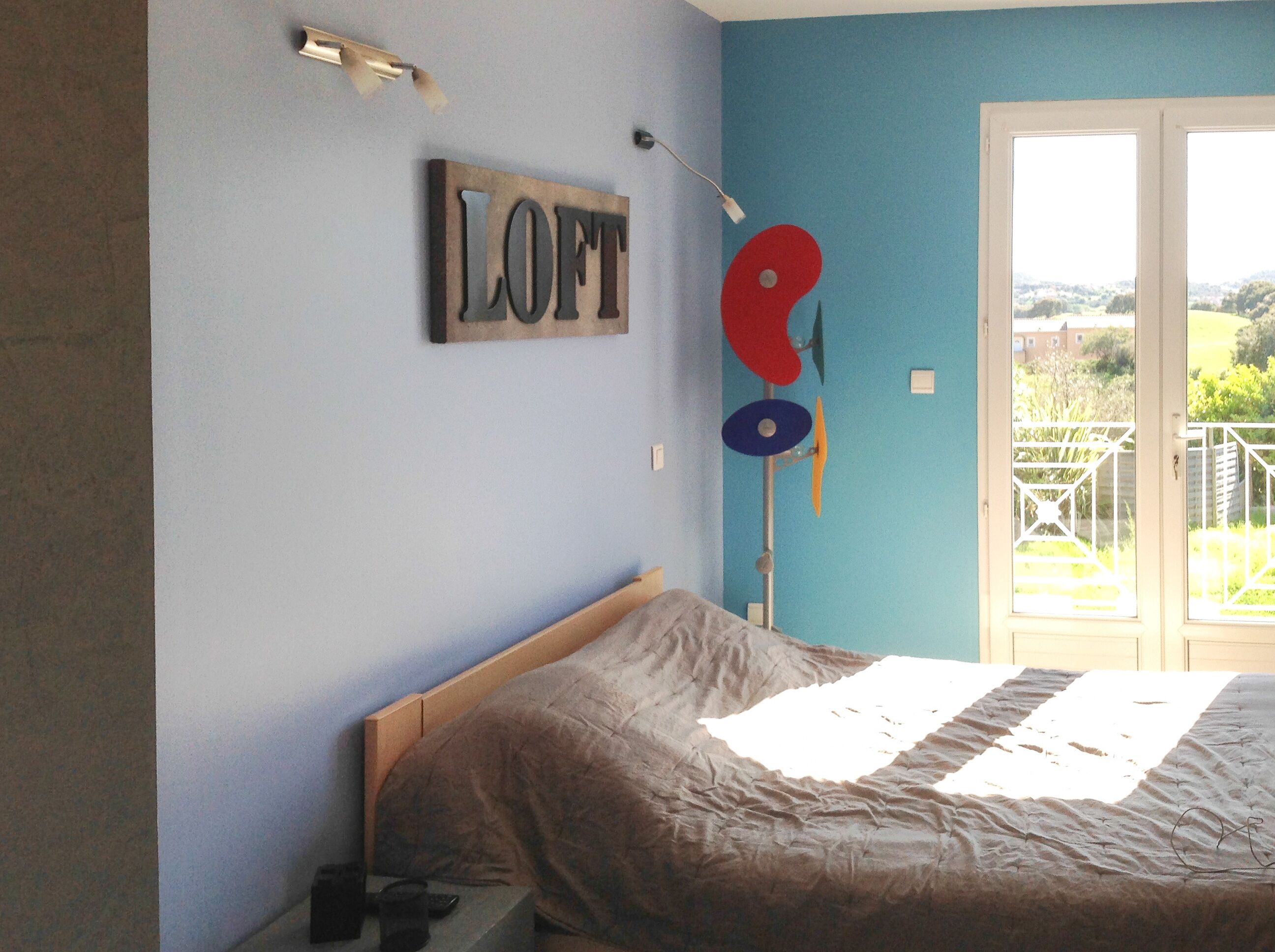 Een slaapkamer met een bed, een bord aan de muur waarop 
