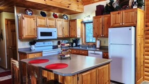 Una cocina con gabinetes de madera, microondas, estufa, lavabo y refrigerador.
