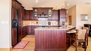 Una cocina amplia con alacenas de madera oscura, una isla central y un comedor con sillas.