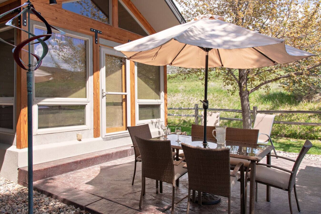 Une terrasse extérieure avec une table et des chaises, un grand parasol et une vue sur un paysage naturel.