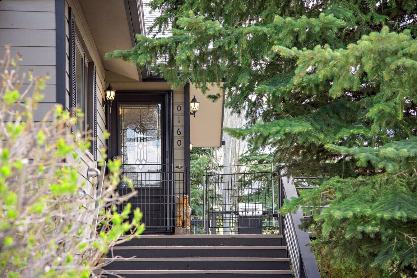 Un escalier menant à une porte sur laquelle est inscrit le numéro « 0160 », le tout étant entouré de verdure.