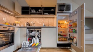 A modern kitchen with an integrated dishwasher, oven, and a refrigerator with a built-in microwave. - Louren Apartments (Prague)