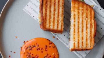 A plate with a grilled sandwich and a side of sauce.