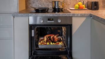 Een keuken met een ingebouwde oven, daarin een gebraden kalkoen en groenten.