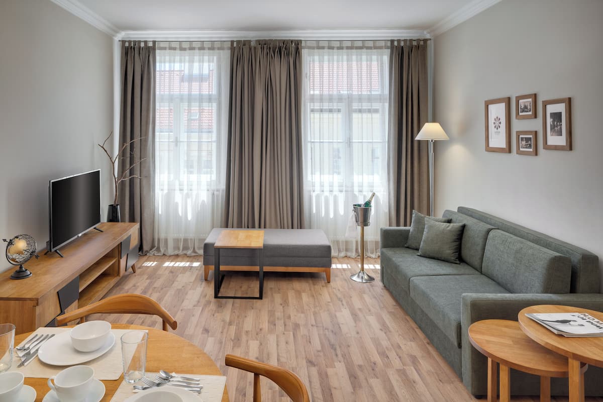 A modern living room with a sofa, a dining table set, a TV, and a lamp.