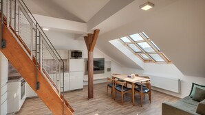 A modern loft with a wooden staircase, a dining area, and a skylight. - Louren Apartments (Prague)