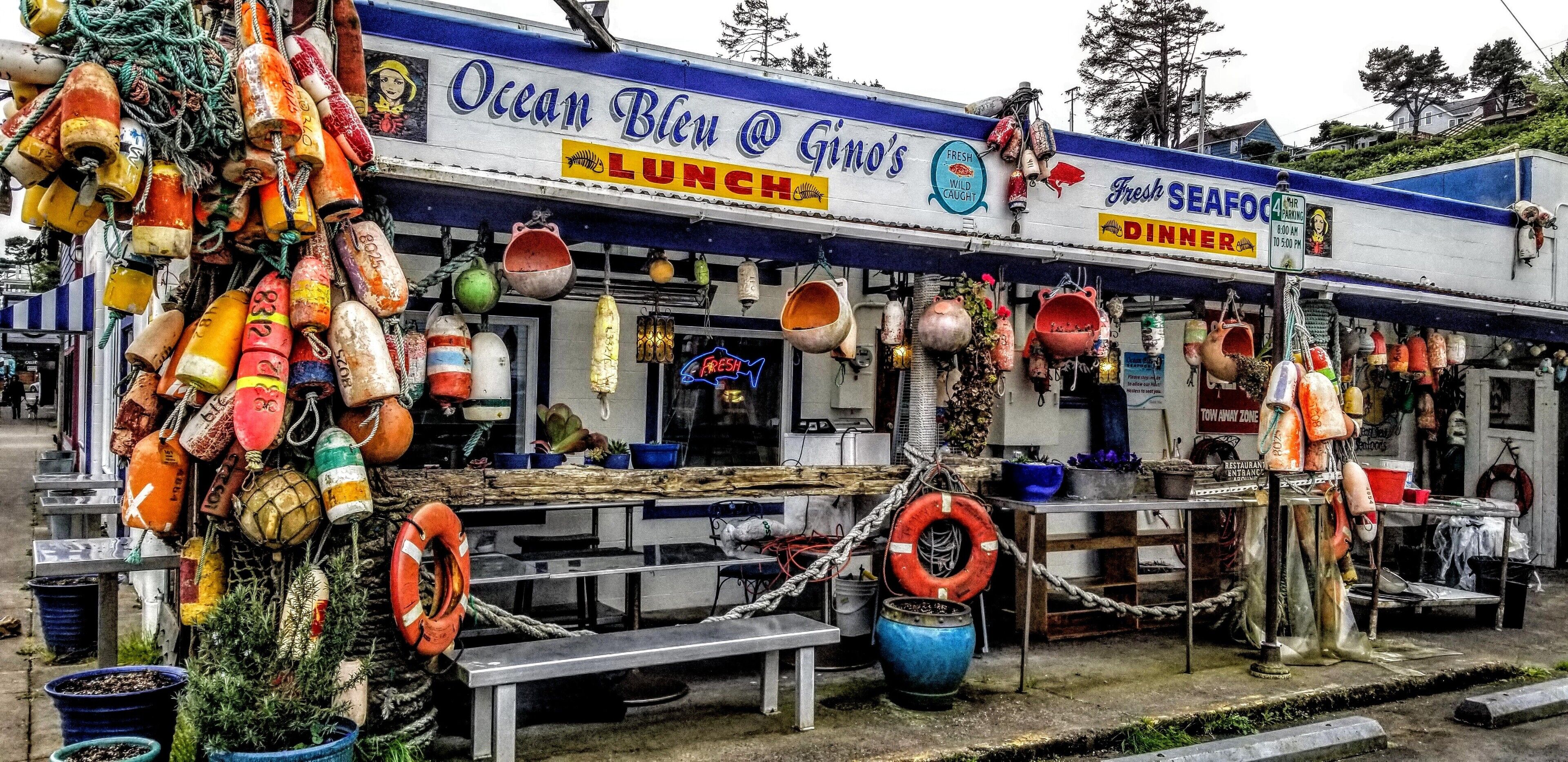 A seafood restaurant named Ocean Bleu with a nautical theme, featuring a signboard, various seafood pots, and life buoys.