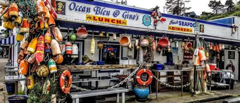 A seafood restaurant named Ocean Bleu with a nautical theme, featuring a signboard, various seafood pots, and life buoys.