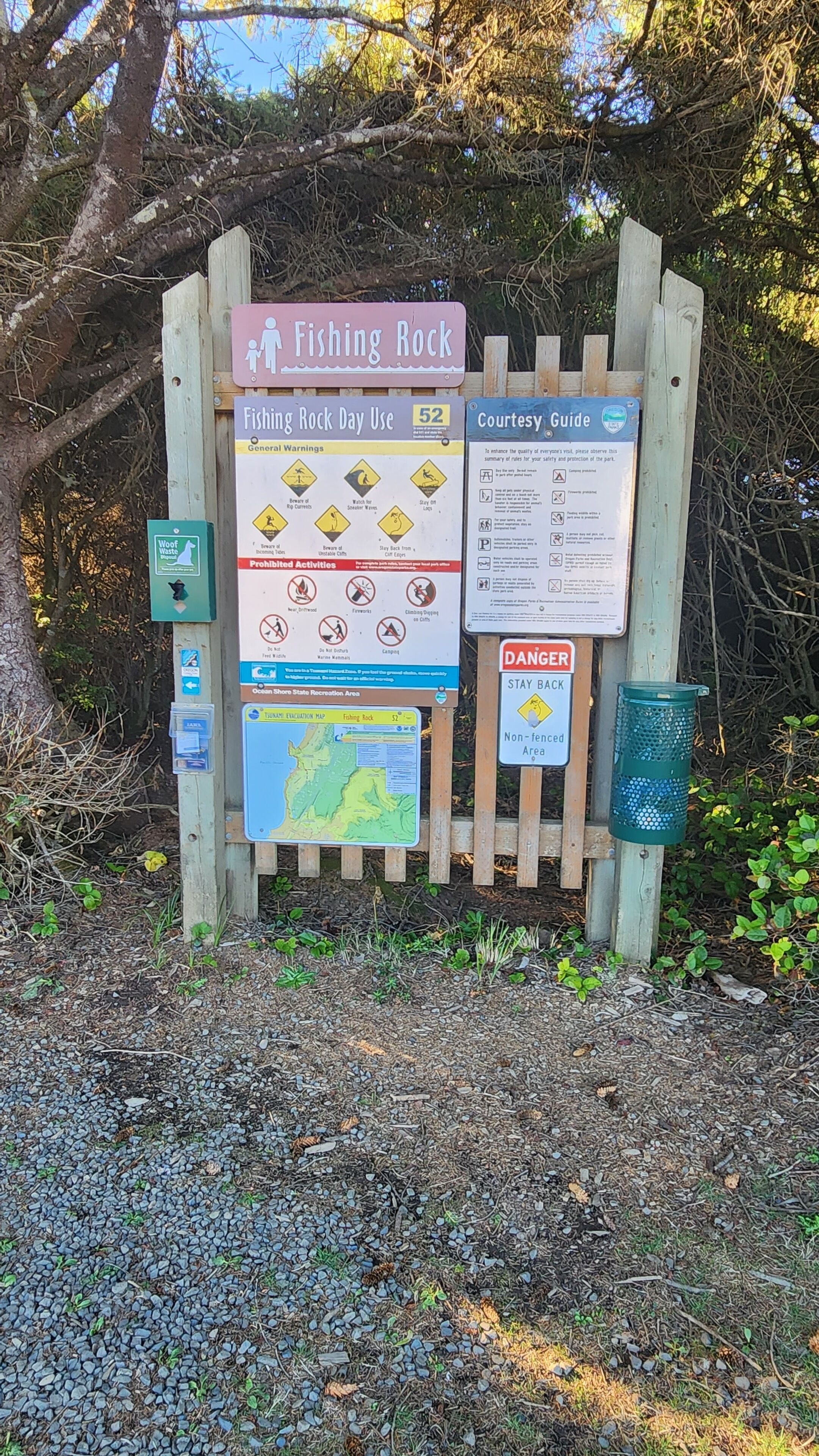 Ein hölzernes Wegweiser mit mehreren Hinweisschildern, darunter eine Karte und Sicherheitshinweise für Fishing Rock.