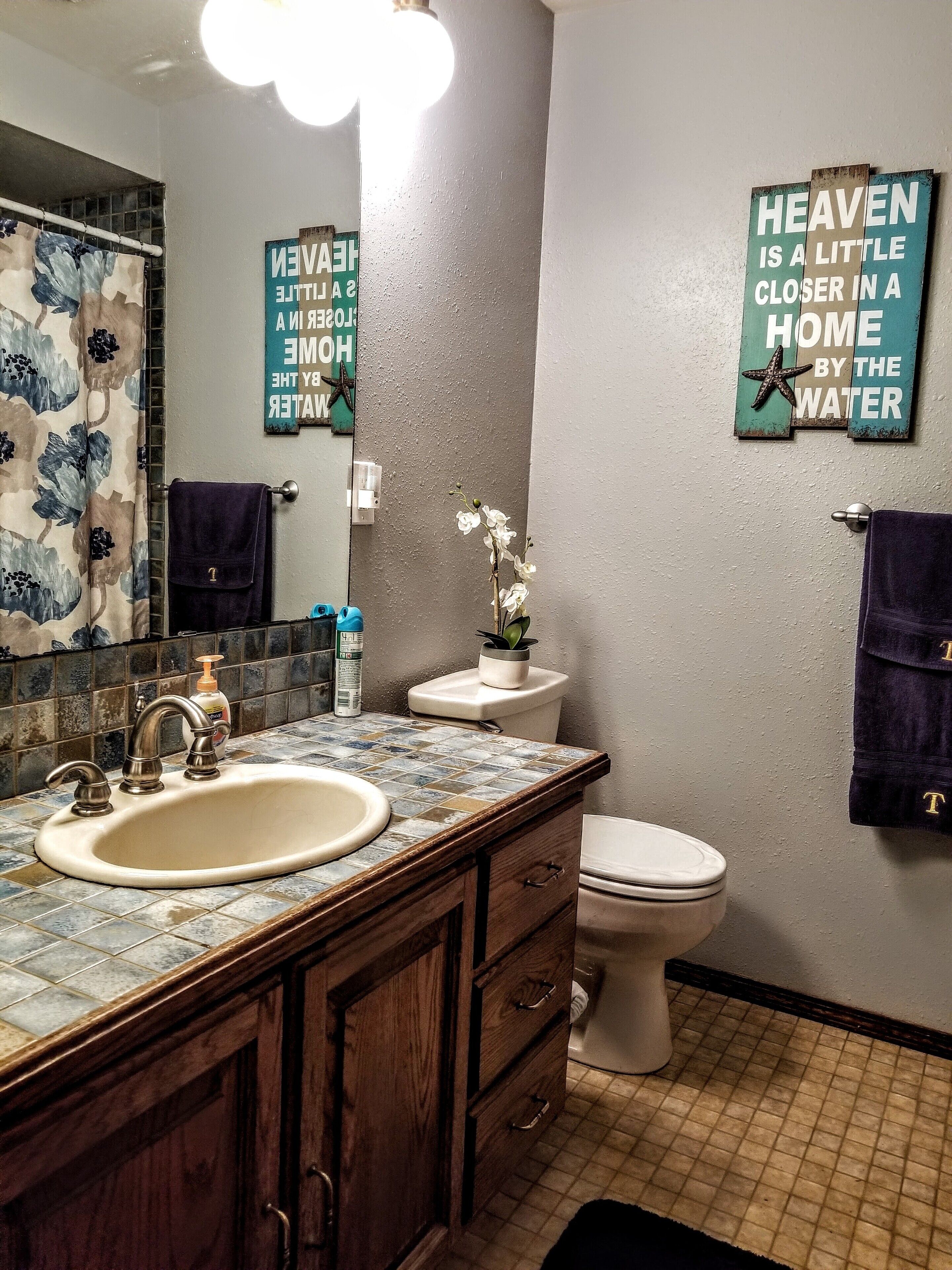 Un baño con lavamanos, inodoro y letreros decorativos en la pared.