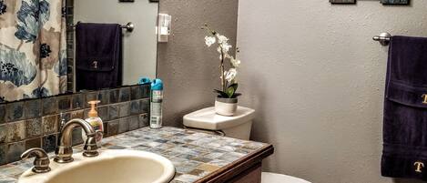Un baño con lavamanos, inodoro y letreros decorativos en la pared.