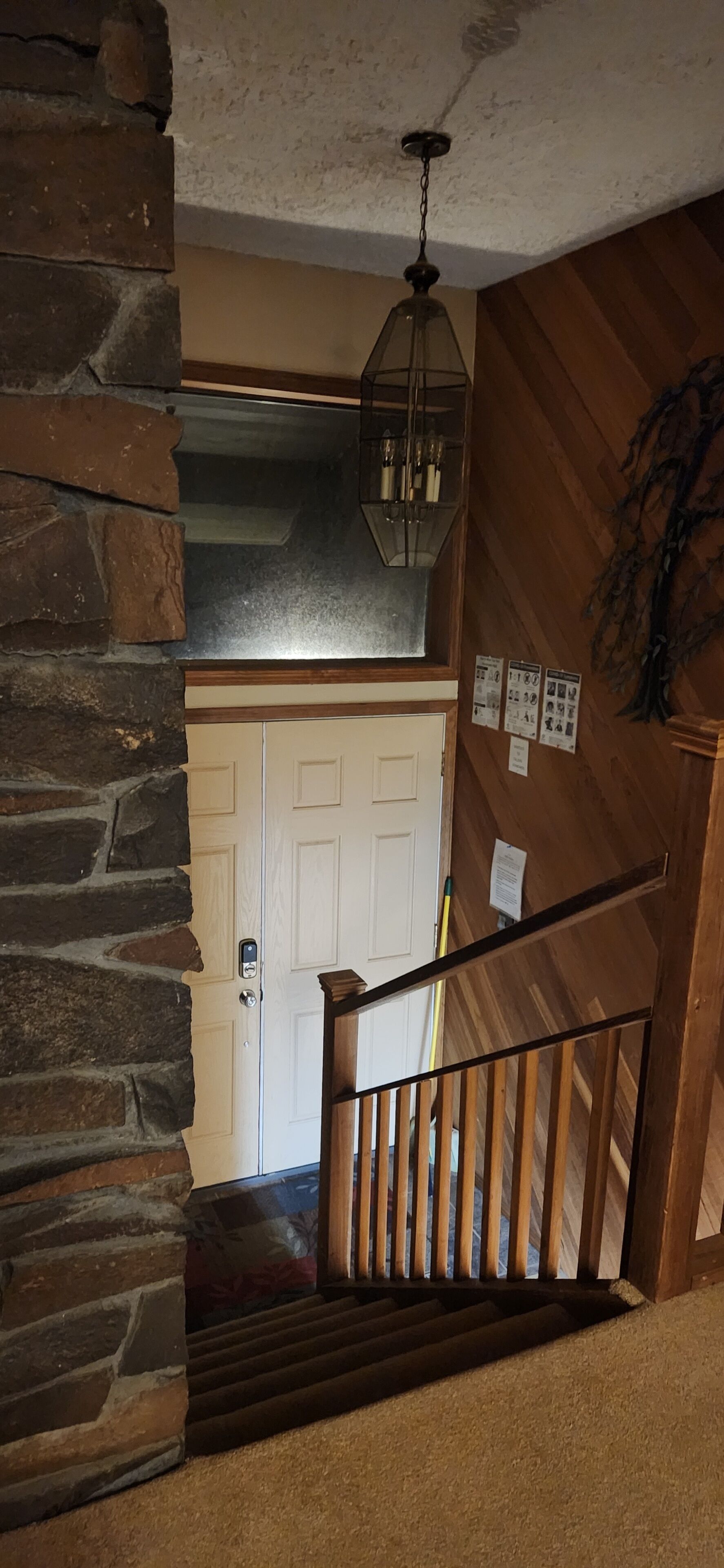 Un escalier en bois, avec un mur en pierre d’un côté et une porte blanche en haut.