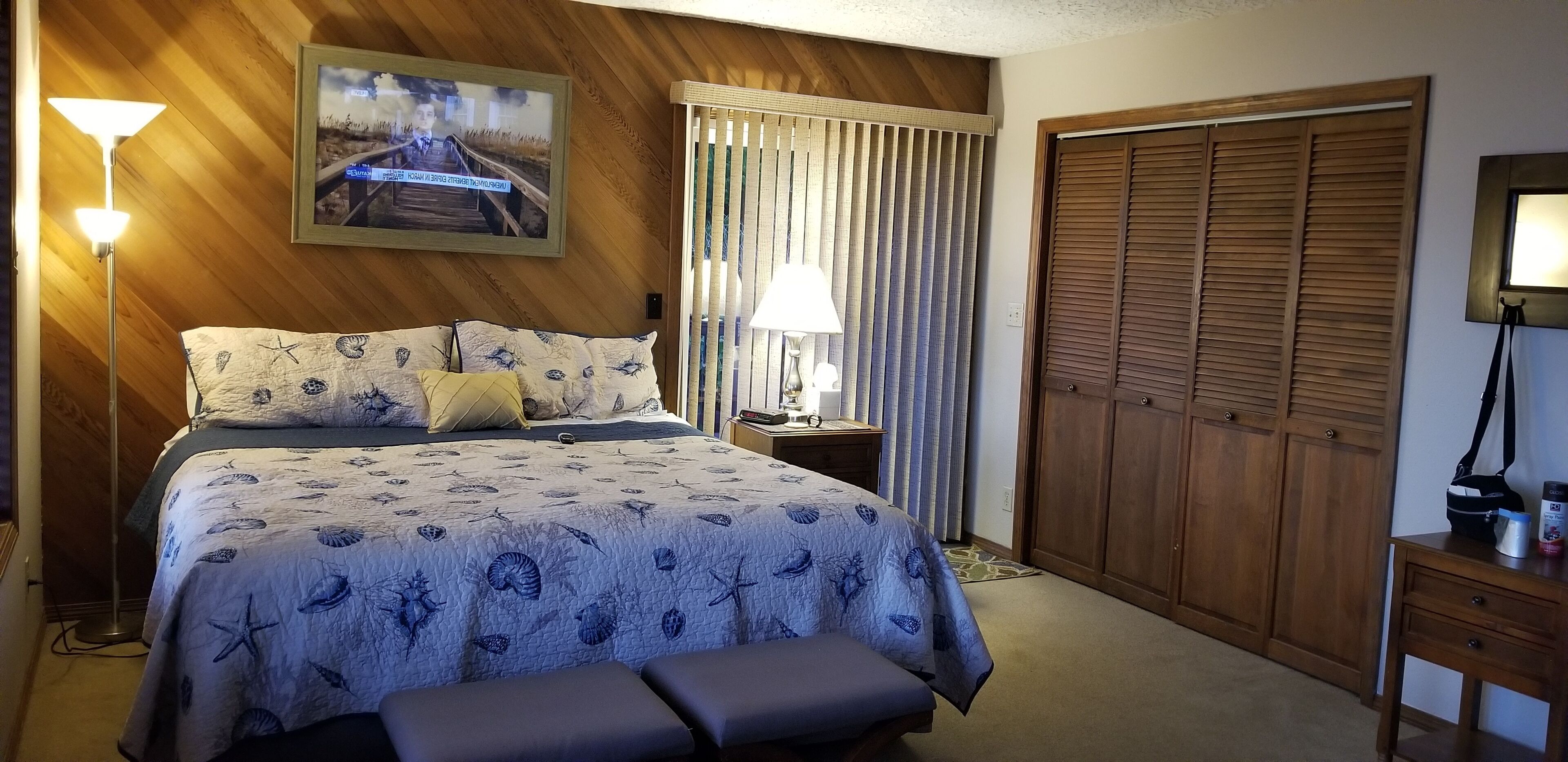 Ein Schlafzimmer mit Bett, Nachttisch, Lampe und Kleiderschrank.