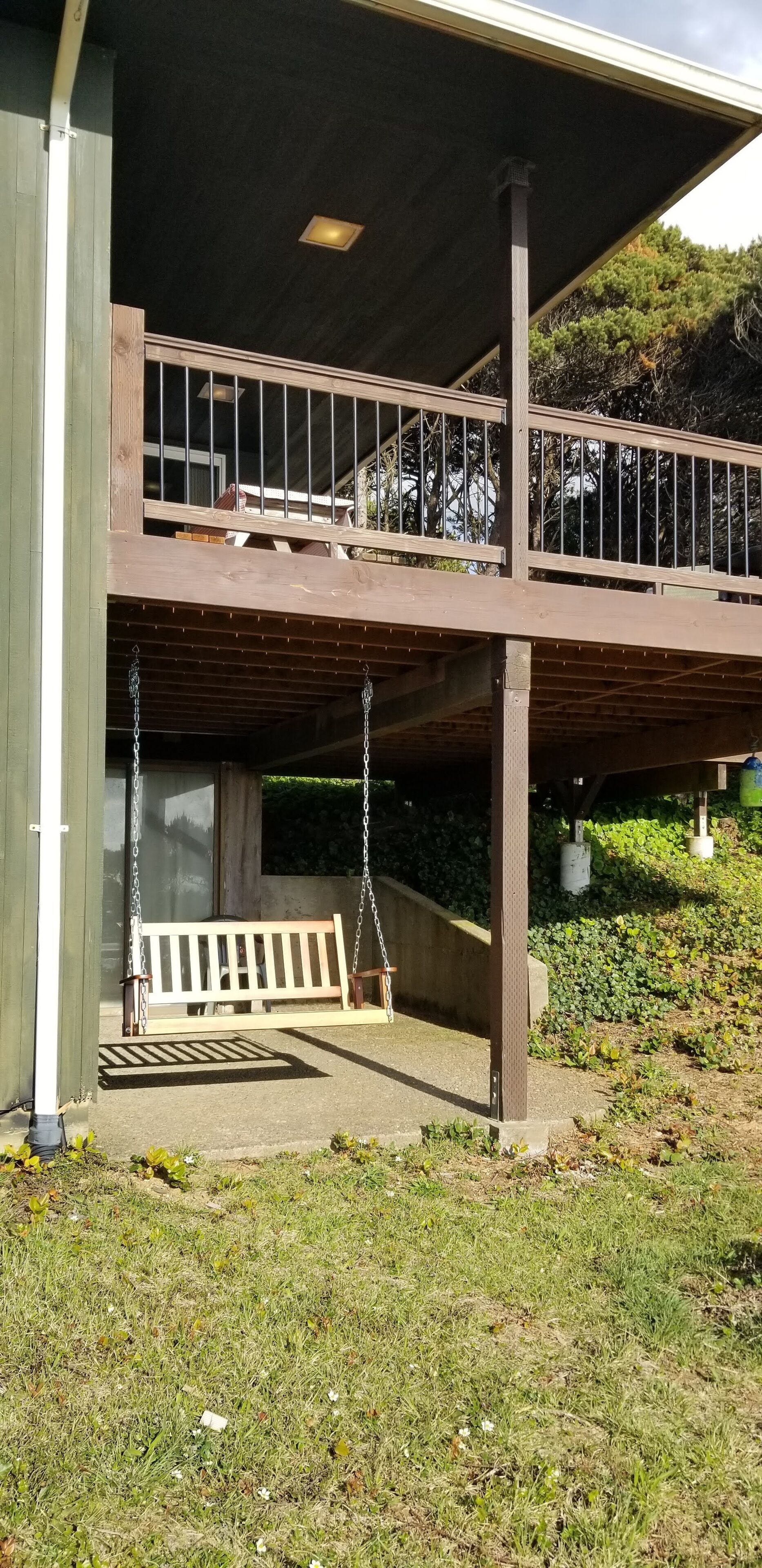 A covered outdoor area with a wooden bench and a swing set.
