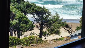 A view of the ocean with waves crashing onto the shore, trees, and a building in the foreground. - 180 degree ocean beach view. Depoe Bay Lincoln beach area.
quick walk to beach 
 (Lincoln Beach)