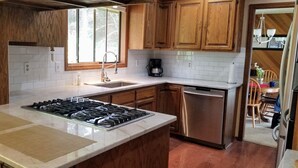 A kitchen with wooden cabinets, a stainless steel dishwasher, a gas stove, and a window providing natural light. - 180 degree ocean beach view. Depoe Bay Lincoln beach area.
quick walk to beach 
 (Lincoln Beach)