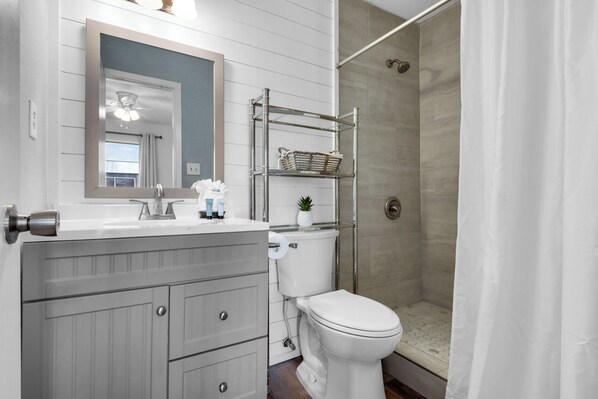 A bathroom with a white vanity, a toilet, a shower with a glass door, and a mirror above the vanity.