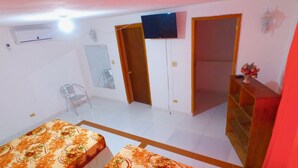 Ein Zimmer mit zwei Betten, einem Fernseher, einem Kleiderschrank und einem Sessel.
