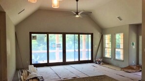 A room with large windows, a ceiling fan, and a view of the outdoors.