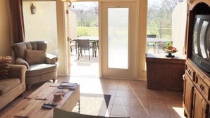 A living room with a sofa, coffee table, and TV stand. There is a sliding glass door leading to an outdoor patio with a table and chairs. - 5 O'Clock Somewhere! WWH302 Apartment 2 New (New Braunfels)