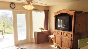 A living room with a wooden cabinet, a ceiling fan, and a sliding glass door leading to a patio. - 5 O'Clock Somewhere! WWH302 Apartment 2 New (New Braunfels)