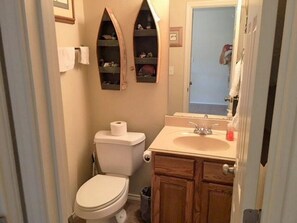 A small bathroom with a toilet, a sink, and two shelves above the toilet. - 5 O'Clock Somewhere! WWH302 Apartment 2 New (New Braunfels)