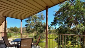 A covered patio with a table and chairs, overlooking a well-maintained lawn and trees. - Good Times & Tan Lines WWi201 Apartment 2 New (New Braunfels)