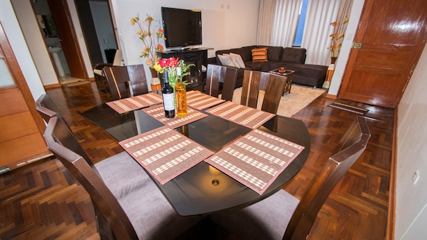 Un comedor con una mesa redonda, sillas y un televisor al fondo.