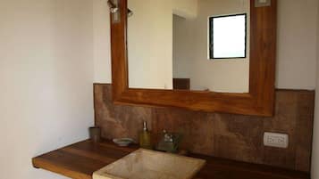 Une salle de bain avec un meuble-lavabo en bois, un grand miroir et un petit lavabo.