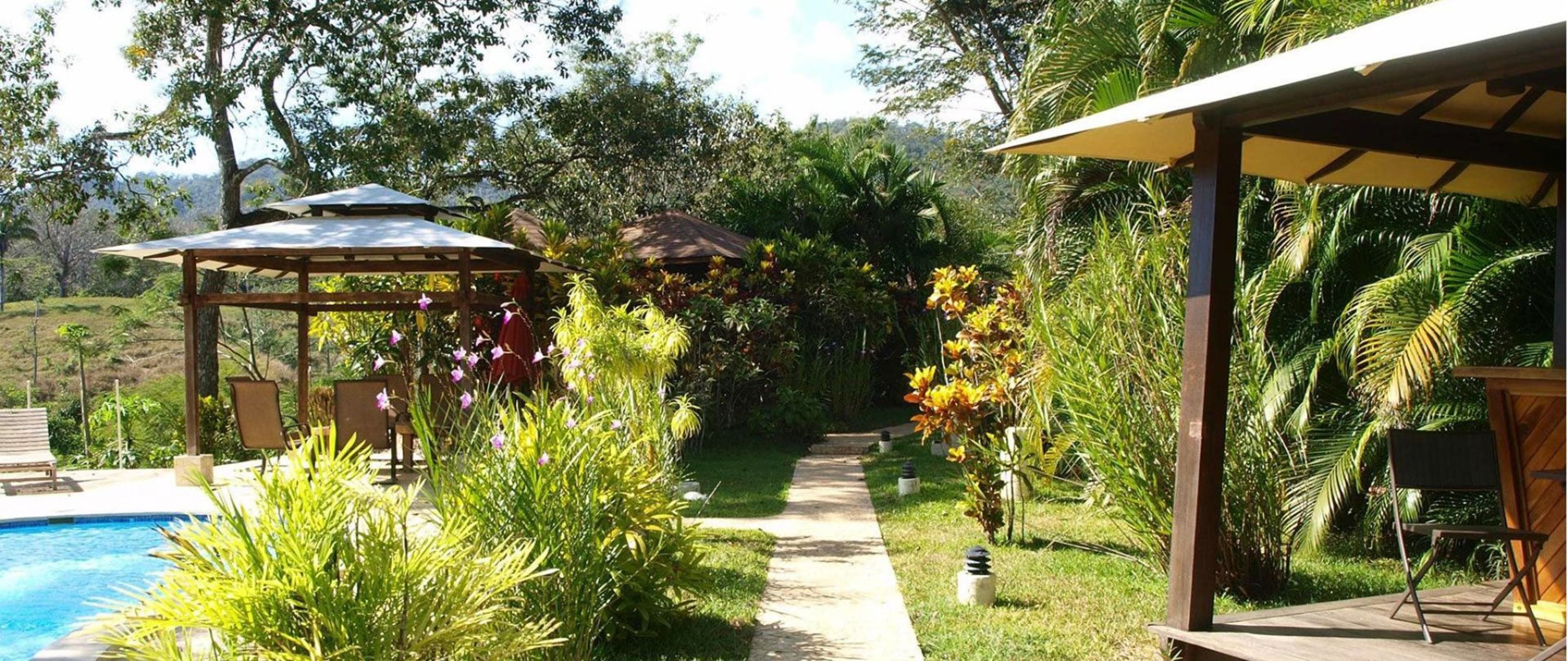 A garden with a pool, a gazebo, and a covered seating area.