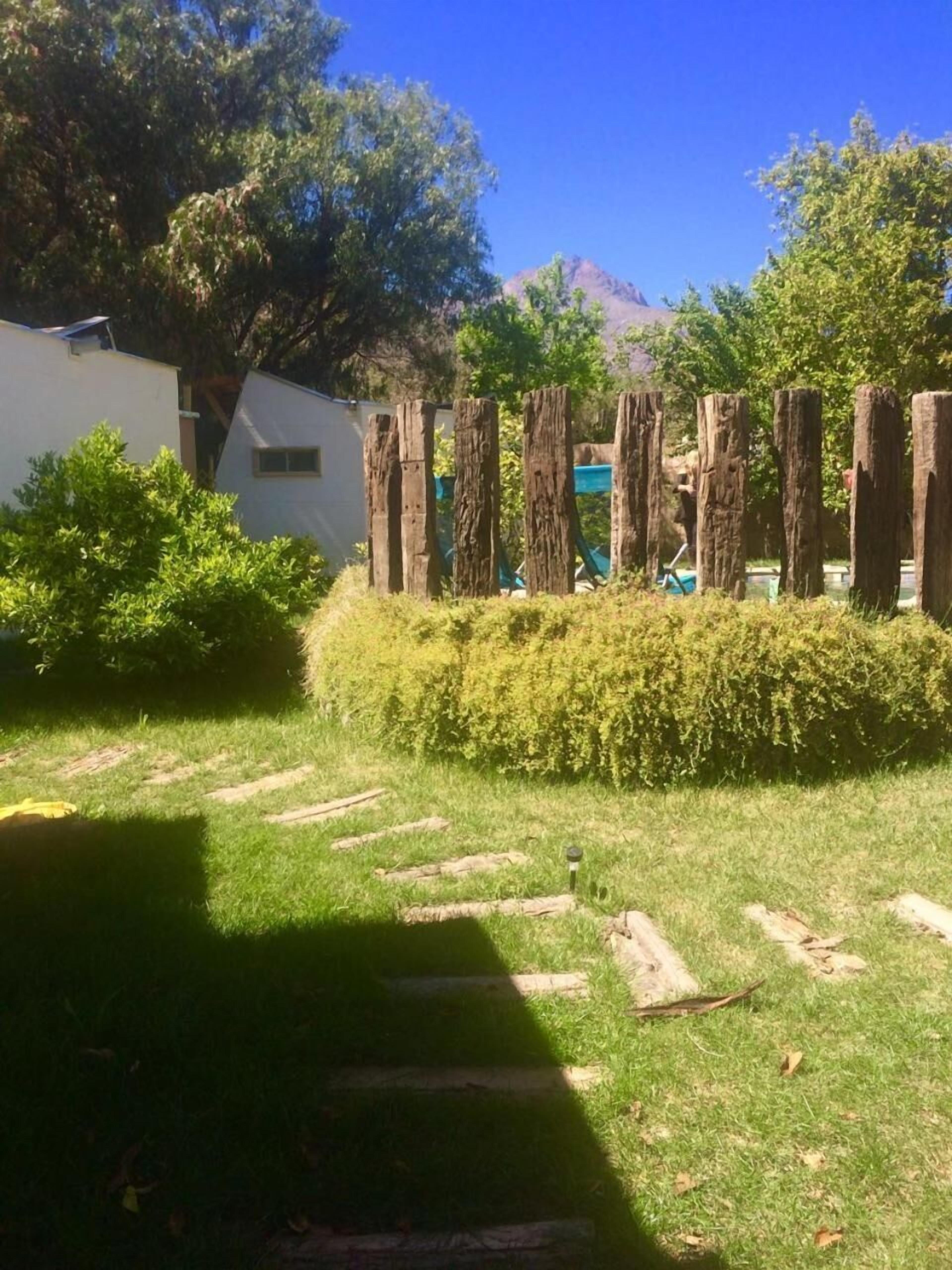 Zona verde con escalones de madera que suben a una valla de madera.
