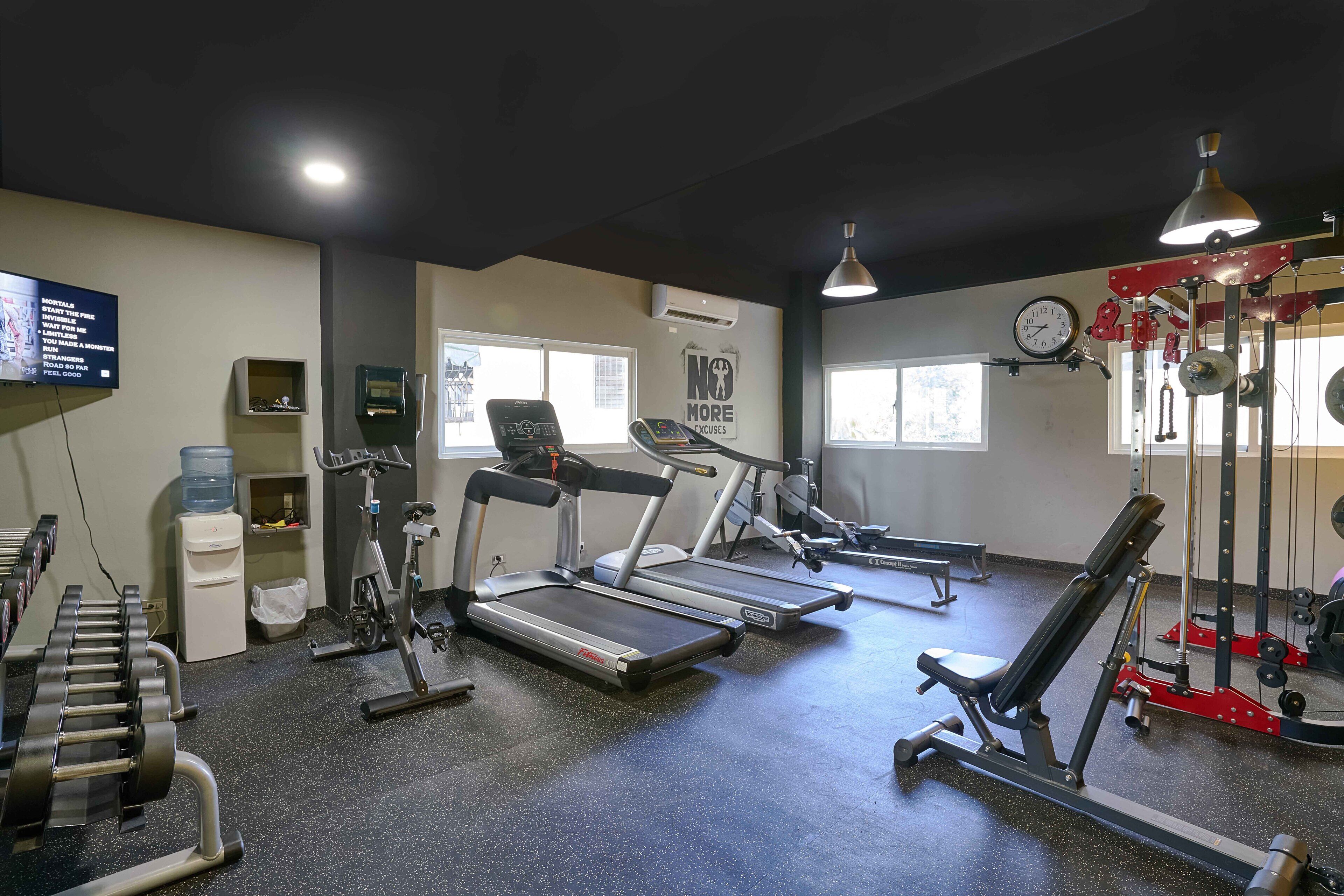 A gym with treadmills, weight machines, and a wall clock.