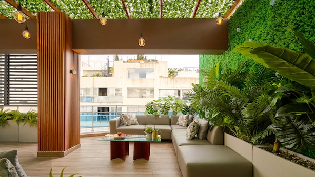 A modern living room with a green wall, wooden panel, and a beige sofa. - Central Park Tower (Santo Domingo)