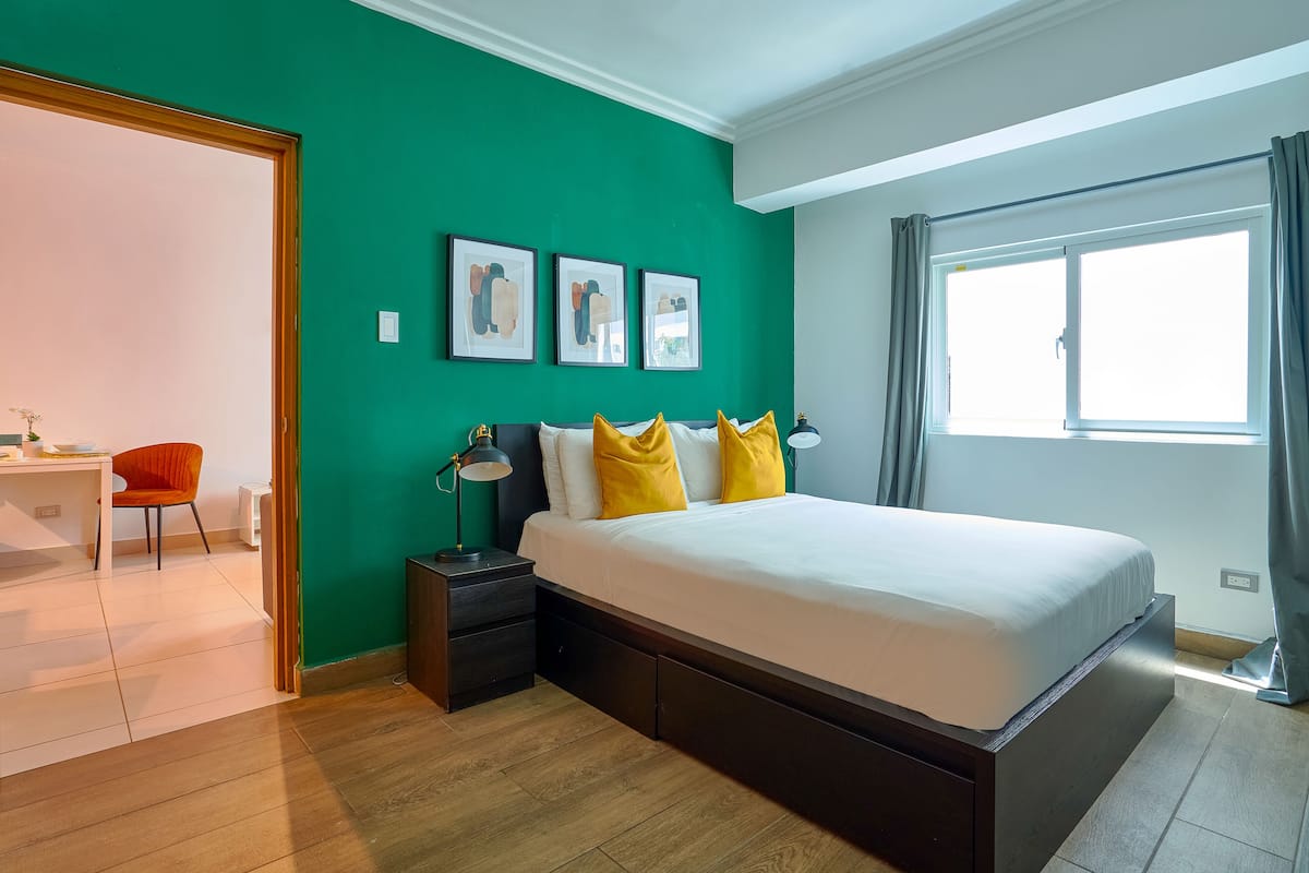 Een moderne slaapkamer met een groot bed, een bureau en een stoel.
