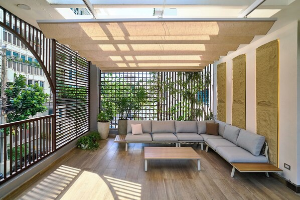A modern living room with a sectional sofa, a wooden coffee table, and a view of a cityscape through a large window. - Central Park Tower (Santo Domingo)